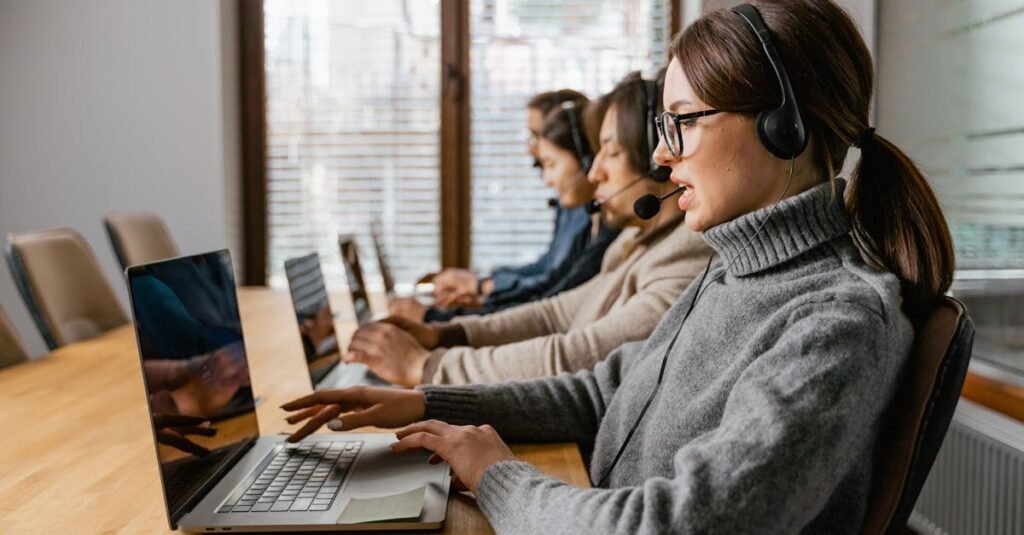 Professional customer service team working in a modern office setting with headsets and laptops.